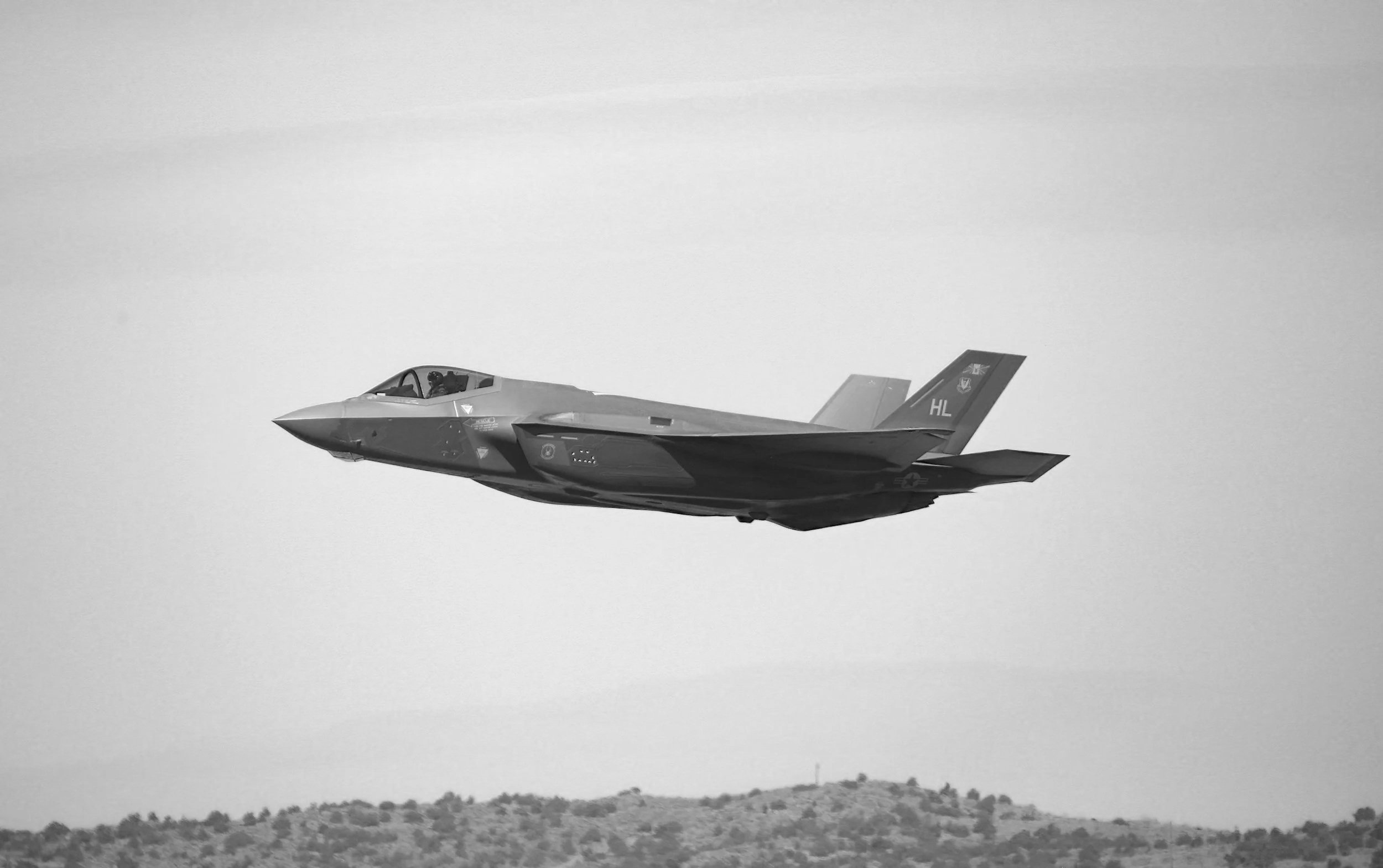 Military aircraft flying above a mountain landscape